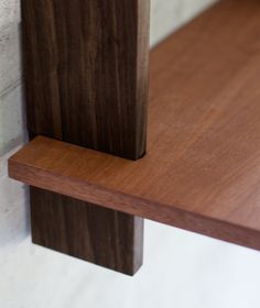 a close up of a wooden shelf against a white brick wall with a wood grained edge