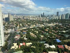 an aerial view of a city with tall buildings and lots of trees in the foreground