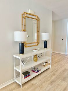 a living room with a white shelf, mirror and lamp on top of the table