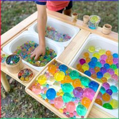 a child is playing with colorful beads in their trays on the table, while another child looks at them