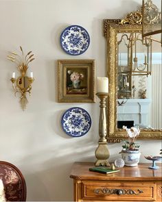 there are three blue and white plates hanging on the wall next to a candle holder