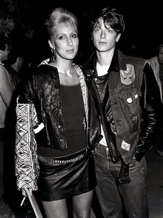 two people standing next to each other in front of a crowd and one person is wearing a leather jacket