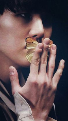 a young man holding a butterfly in his mouth while looking at it's reflection