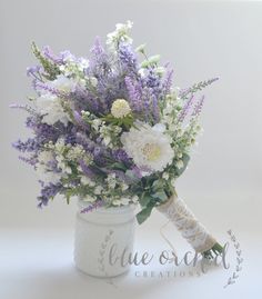 a bouquet of white and purple flowers in a mason jar