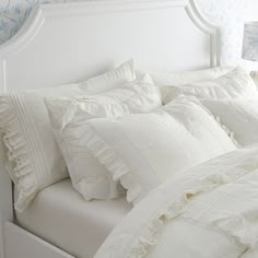 a white bed topped with lots of pillows