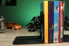 three books are stacked on top of each other in front of a toy car and tree