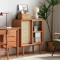 a room with a chair, desk and bookshelf on the floor next to a potted plant