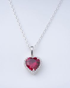 The simple yet awe-inspiring design of this pendant will snatch hearts. The ruby is guarded by immaculately arranged white stone making a pretty design to adorn on special occasions to embody elegance. GENDER: Female MATERIAL: 925 Sterling Silver CHAIN TYPE: Diamond Cut Curb Chain CLASP TYPE: Spring Ring Clasp PENDENT HEIGHT: 0.84 INCH STONE 1 TYPE: Gemstone STONE 1 SHAPE: Heart STONE 1 COLOURE: Ruby STONE 2 TYPE: Diamond STONE 2 SHAPE: Round STONE 2 COLOURE: White  TOTAL WEIGHT: 5.10 GRAM TO 5. Ruby Heart Charm Pendant Necklace, Ruby Heart Pendant Necklace For Wedding, Red Gemstone Heart Pendant Necklace, Silver Ruby Heart Cut Necklace, Present For Girlfriend, Best Gift For Wife, Bow Bracelet, Sterling Silver Jewellery, Silver Bow