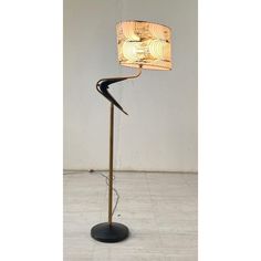 a floor lamp with a wooden shade on it's side and a black base