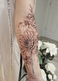 a woman's arm with black and white flowers on the left side of her arm