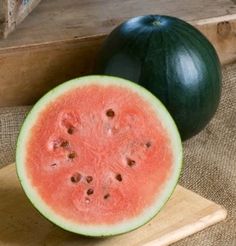 two pieces of watermelon sitting on top of a cutting board next to each other