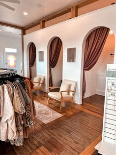 a clothing store with clothes on hangers and chairs in front of the window,