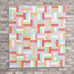 a colorful quilt hanging on the side of a brick wall