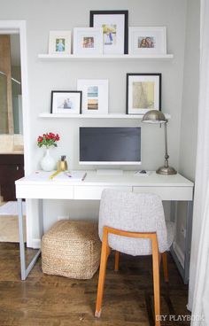 a white desk topped with a computer monitor next to a wooden floor covered in pictures