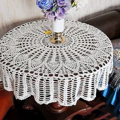 a white doily on a table with flowers in a vase sitting next to it