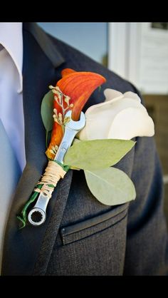 a boutonniere with an orange and white flower attached to the lapel of a suit