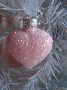 a pink heart ornament hanging from a christmas tree