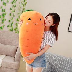 a woman hugging a giant stuffed carrot pillow