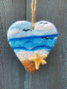 a heart shaped ornament hanging on a wooden fence with a starfish and ocean scene