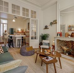 a living room filled with furniture and a fire place in front of a kitchen area