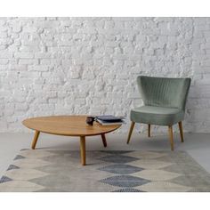 two chairs and a table in front of a white brick wall with a rug on the floor