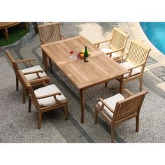 an outdoor table and chairs next to a pool with a bottle of wine on it