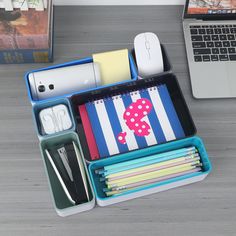 an open laptop computer sitting on top of a desk next to stationery and office supplies