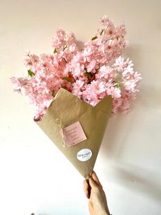 a person holding a brown envelope with pink flowers in it