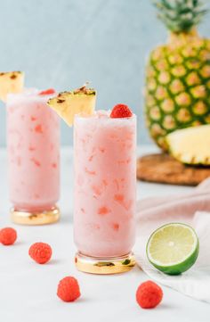 two pineapple margaritas with raspberries on the rim and one garnished