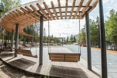 a wooden bench sitting under a canopy next to a park filled with benches and swings