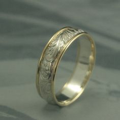 a wedding ring with an engraved design on the inside and outside, sitting on a gray surface