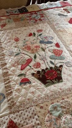 a quilted bed with an embroidered crown on the top and red flowers on the bottom