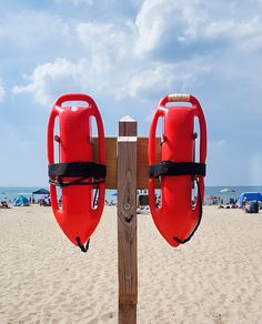 two life vests attached to a wooden post on the beach