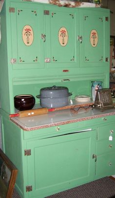 an old fashioned kitchen with green cupboards and cooking utensils on the counter