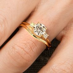 a woman's hand with a yellow and white diamond ring on top of her finger