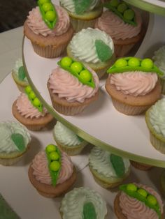 cupcakes with green and pink frosting on a white plate next to other cupcakes