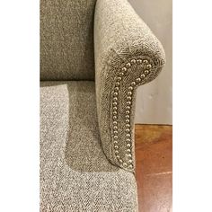 an upholstered chair with beading on the arm and back, in grey tweed