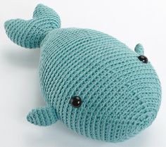 a knitted stuffed animal is laying on the floor with its head turned to look like a whale