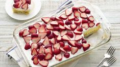 there is a cake with strawberries on it and two forks next to the cake