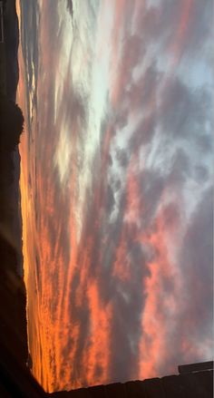 an orange and pink sky with clouds in the background