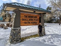 a woman standing in front of a sign for the mountains shall bring peace to the people