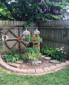 an outdoor garden with lots of flowers and plants in the center, along side a fence