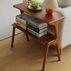 a table with books and a bowl of grapes on it next to a white couch