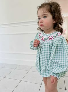 CHRISTMAS PREORDER! EXPECTED TO SHIP BY EARLY NOVEMBER! The Blakely Smocked Gingham Bishop Dress is a holiday staple for your little girl! A hand-embroidered detailed bow and holly design add a cheerful touch to this dress! Items purchased together will ship out together. Please place a separate order for all ready to ship items.  Clothing Care Instructions: Machine wash gentle. Do not bleach. Tumble dry delicate at low heat. Iron at medium. If the item that you are ordering has red or another b Christmas Smocked Dresses Baby, Christmas Smocked Outfits, Christmas Smocked Dresses, Baby Smocked Outfits, Christmas Baby Clothes, Red Bow Christmas, Toddler Smock, Smocked Christmas Dresses, Smocked Baby Clothes