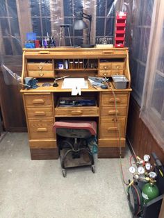 an old wooden desk with lots of clutter on it