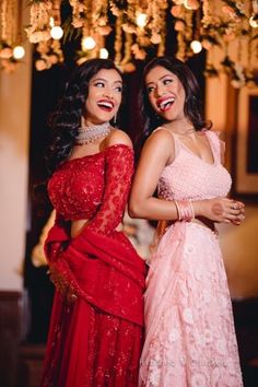 two women standing next to each other in red dresses and one is wearing a pink dress