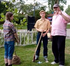 three people standing in the grass holding shovels