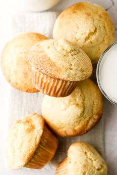 some muffins and a glass of milk on a white tablecloth next to it