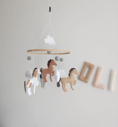 a baby mobile with horses hanging from it's sides and the word child spelled out