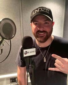 a man wearing a hat and holding a microphone in front of a recording studio booth